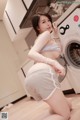 A woman is posing in front of a washing machine.