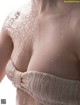 A woman in a white bra with water droplets on her breasts.