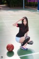 A woman kneeling on a basketball court with a ball.