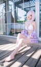 A woman in a white bikini sitting on a wooden deck.