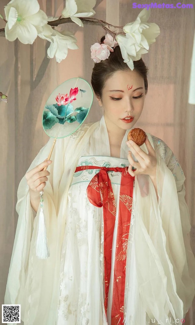 A woman in a white and red dress holding a fan.