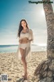 A woman standing on a beach next to a palm tree.