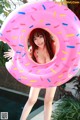 A woman in a bikini holding a pink donut shaped pool float.