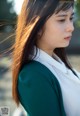 A woman with long brown hair wearing a green jacket.