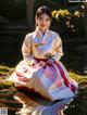 A woman in a hanbok sitting in the water.