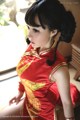 A woman in a red dress sitting on a window sill.